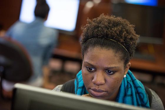 Photo of a Chatham University student concentrating while working on a desktop computer. 